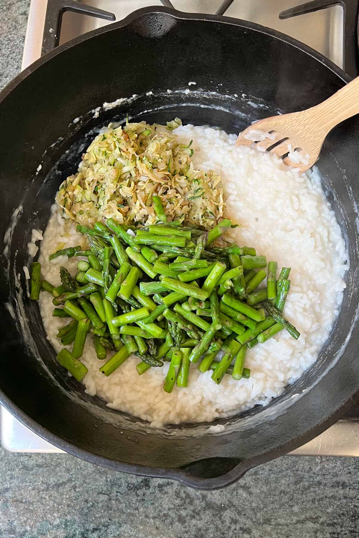 shredded sautéed zucchini and sautéed asparagus added on top of creamy risotto rice in a large Dutch oven