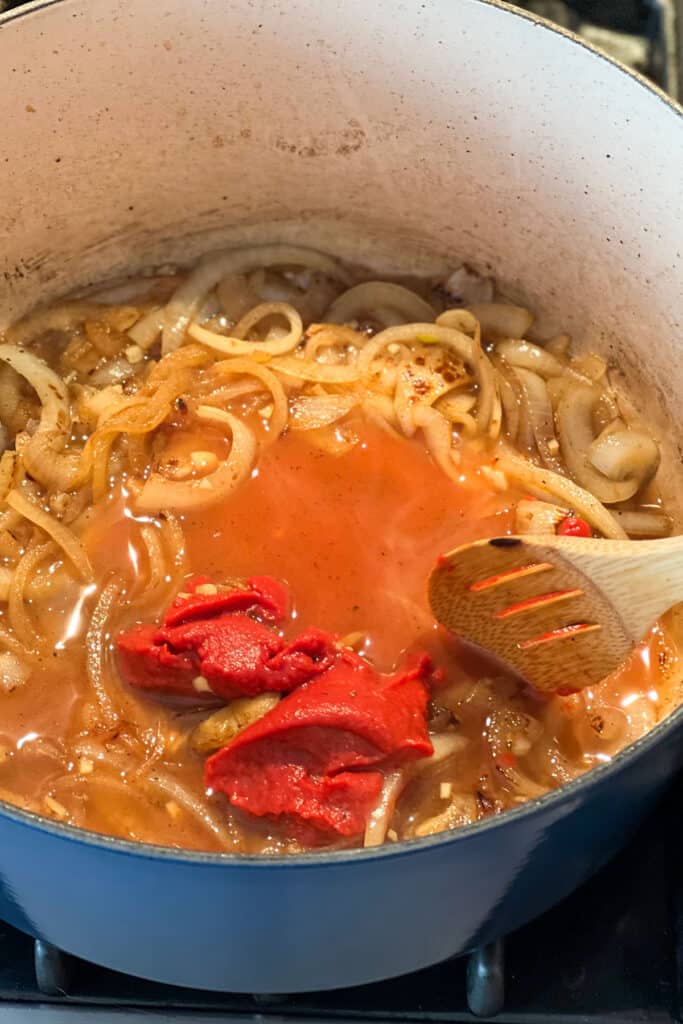 tomato past added to a stew pot with onions and wine