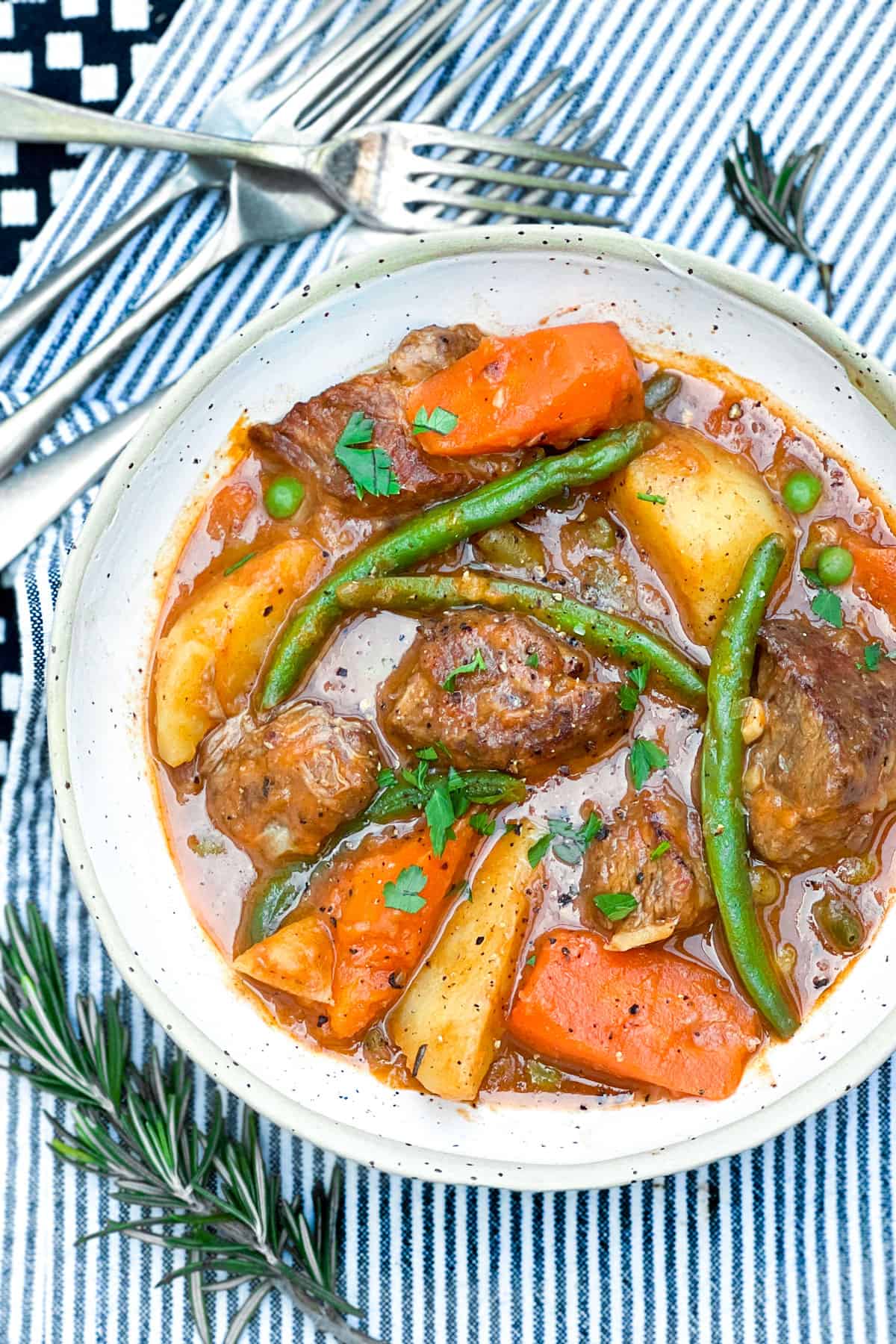 bowl of lamb stew with potatoes, green beans, carrots and peas.