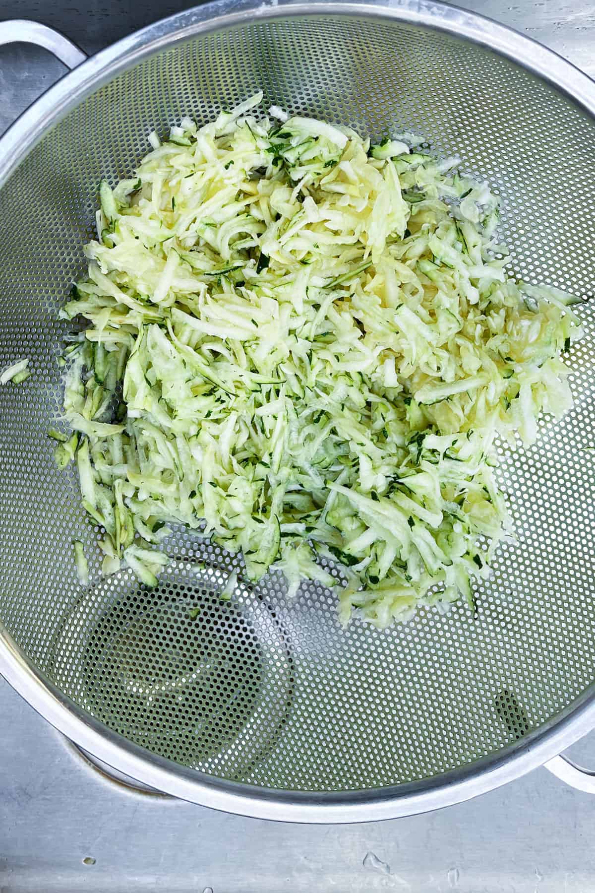 grated zucchini and summer squash salted and draining in a mesh colander