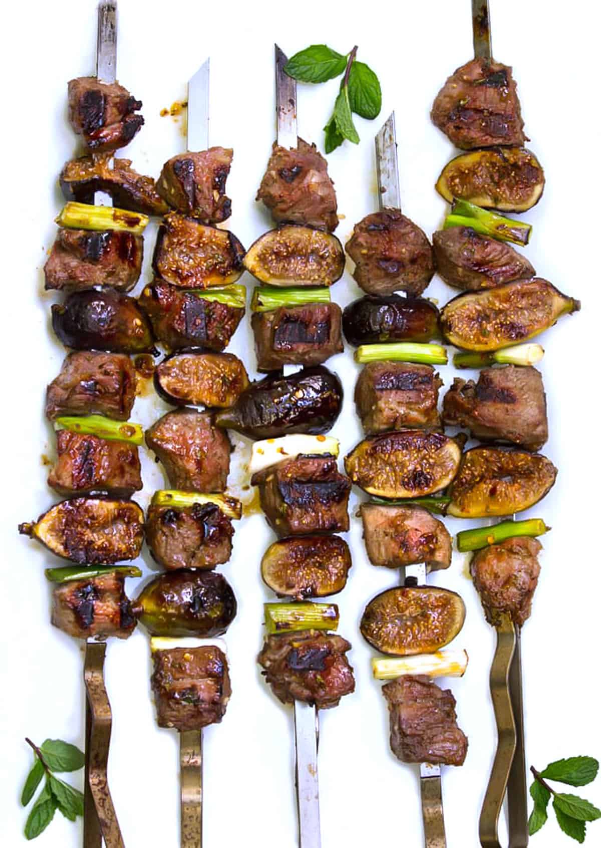5 lamb and fig kebabs on a white platter