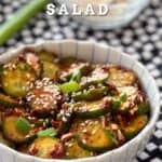 a bowl of korean cucumber salad on top of black and white dish towels