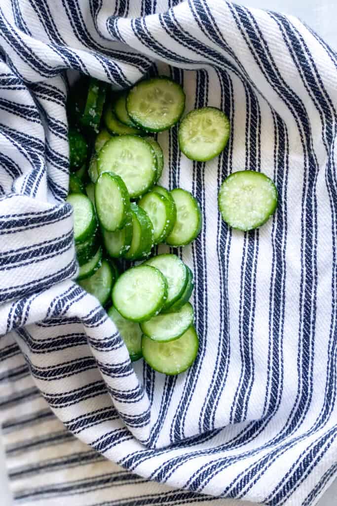 sliced salted cucumbers in a tea towel