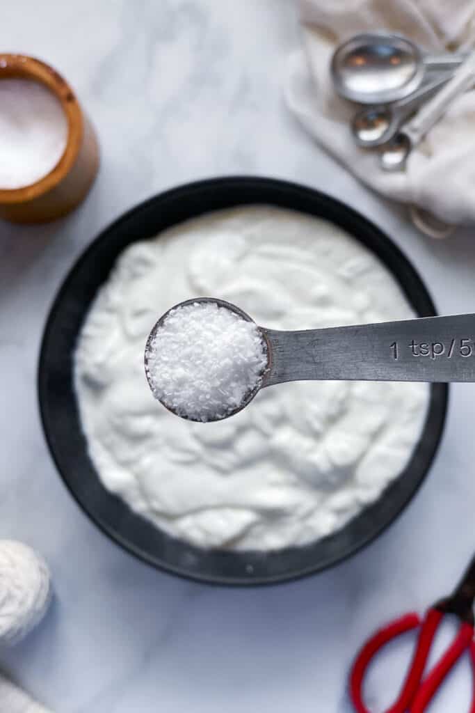 teaspoon of salt over bowl of bulgarian yogurt