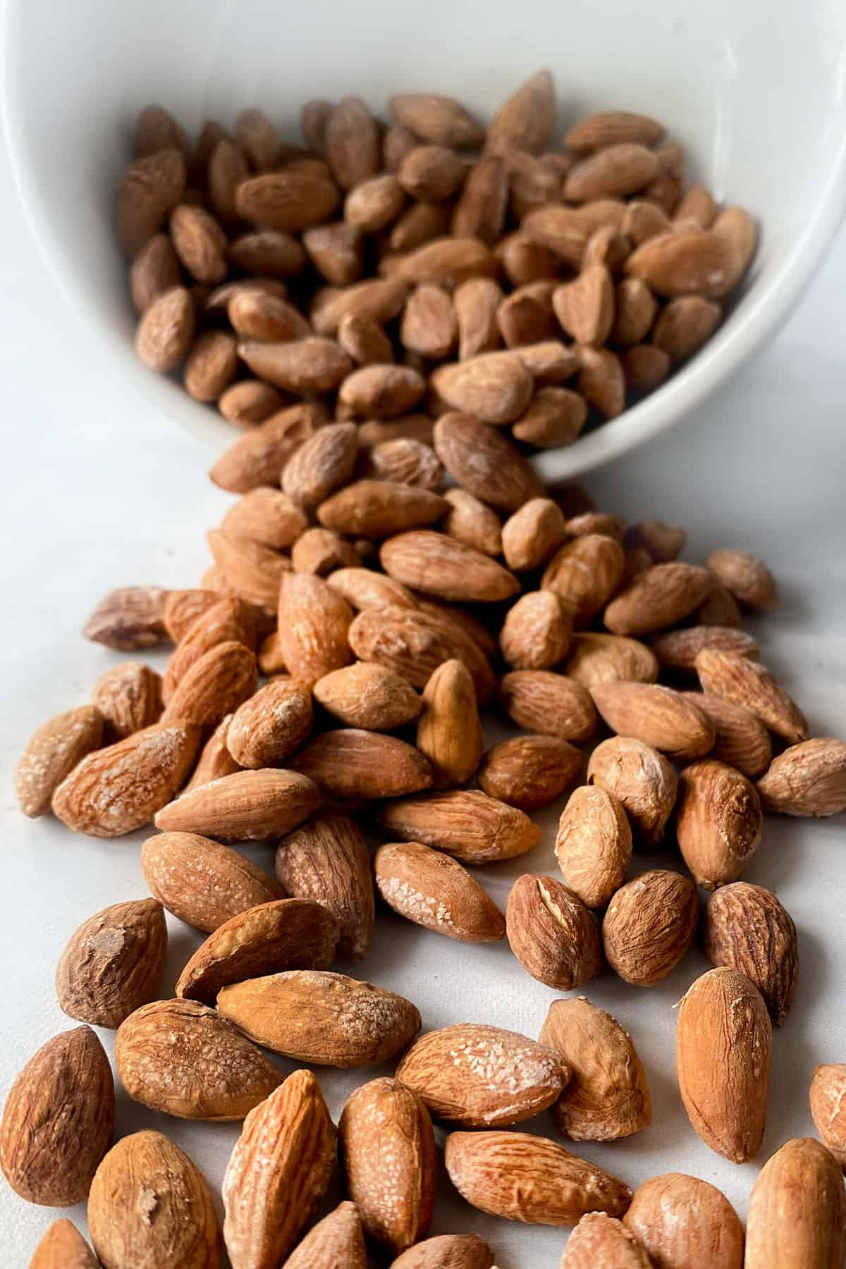 Salted almonds spilling out of a bowl onto a counter