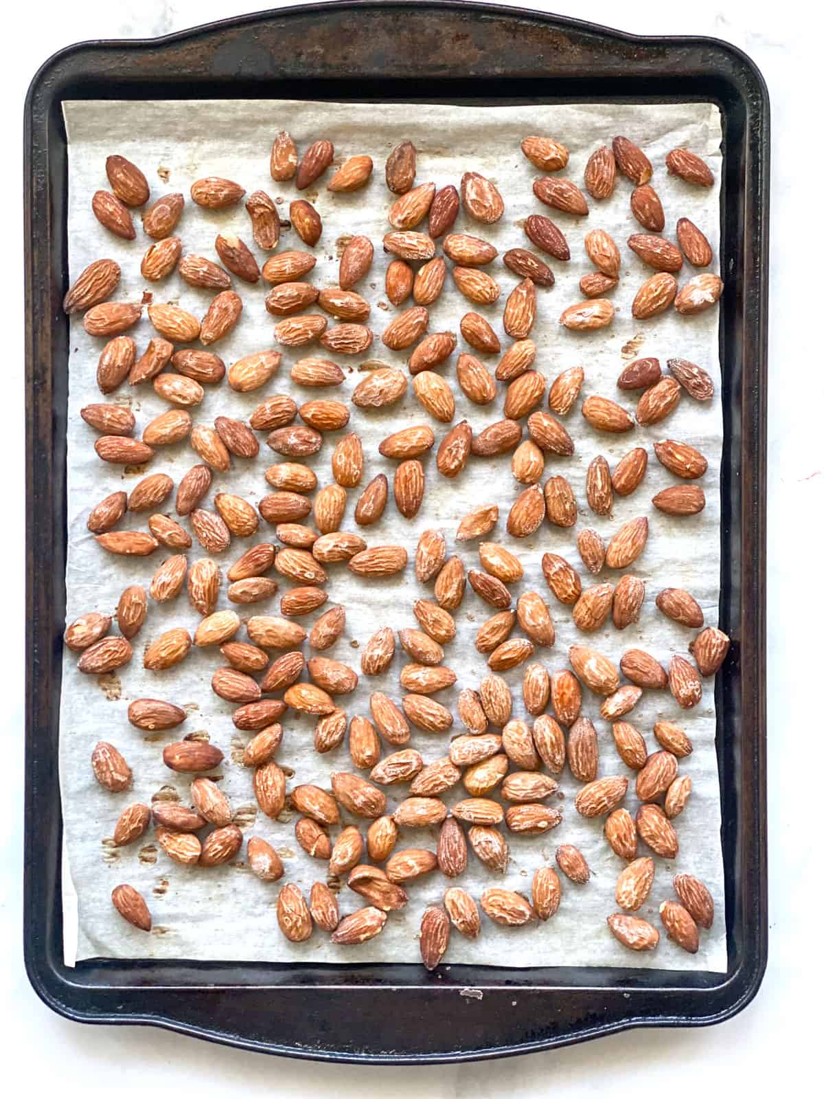 A parchment lined baking sheet with salted roasted almonds on it