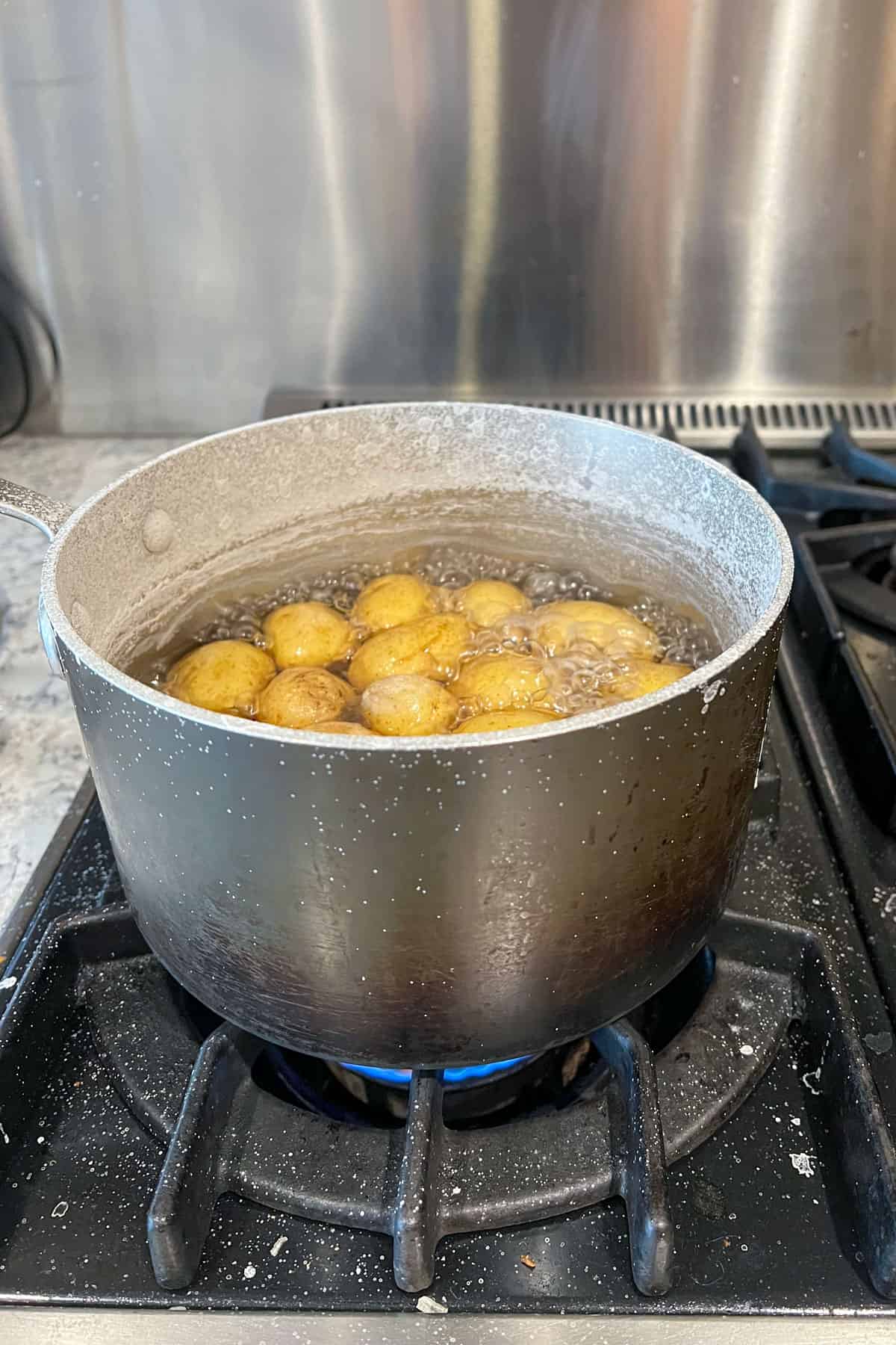 Pot filled with small new potatoes boiling in salt brine on the stovetop.