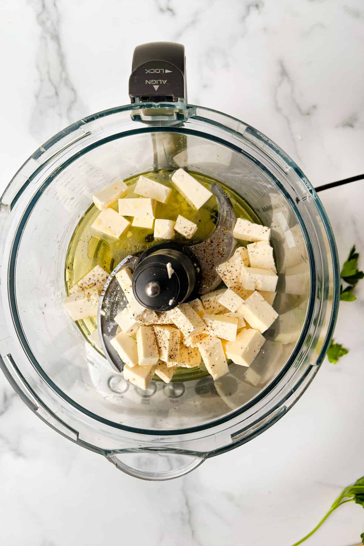 Cubes of feta, olive oil, lemon juice, salt and pepper in the bowl of a food process.