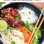 Vietnamese Noodle Salad Bowl filled with piles of ingredients: vermicelli rice noodles, caramelized pork, shredded carrots, cabbage and cucumbers, and bean sprouts. Chopsticks resting on the edges of the bowl.