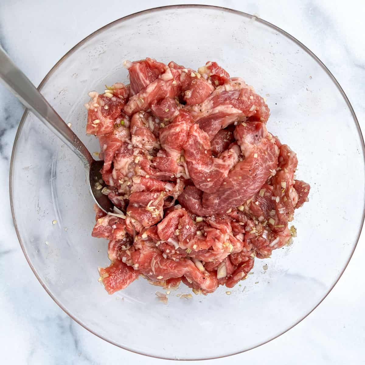 Glass bowl filled with sliced pork should coated in lemongrass marinade