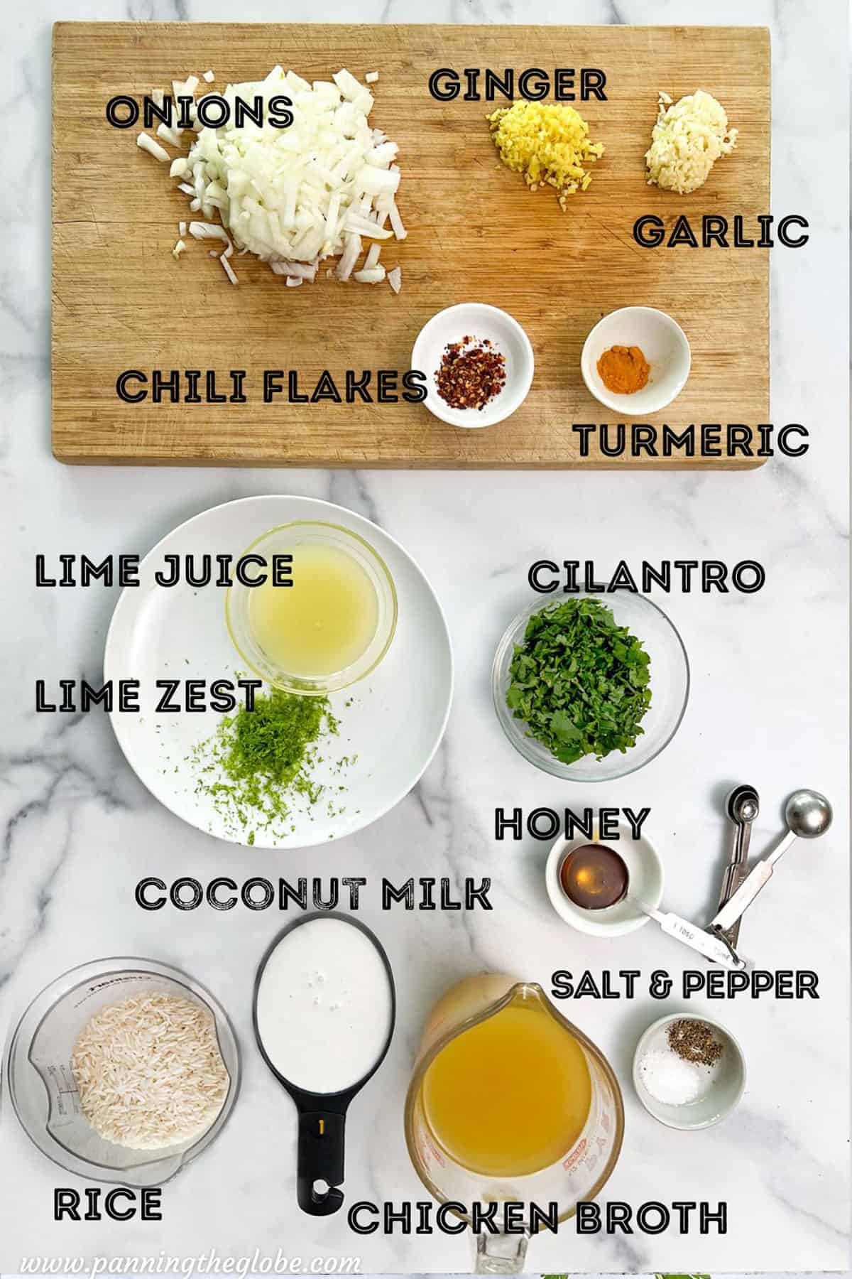 Prepped ingredients on a marble counter: chopped onions, garlic, ginger, cilantro, lime zest, lime juice, coconut milk, rice, honey turmeric, and chili flakes.