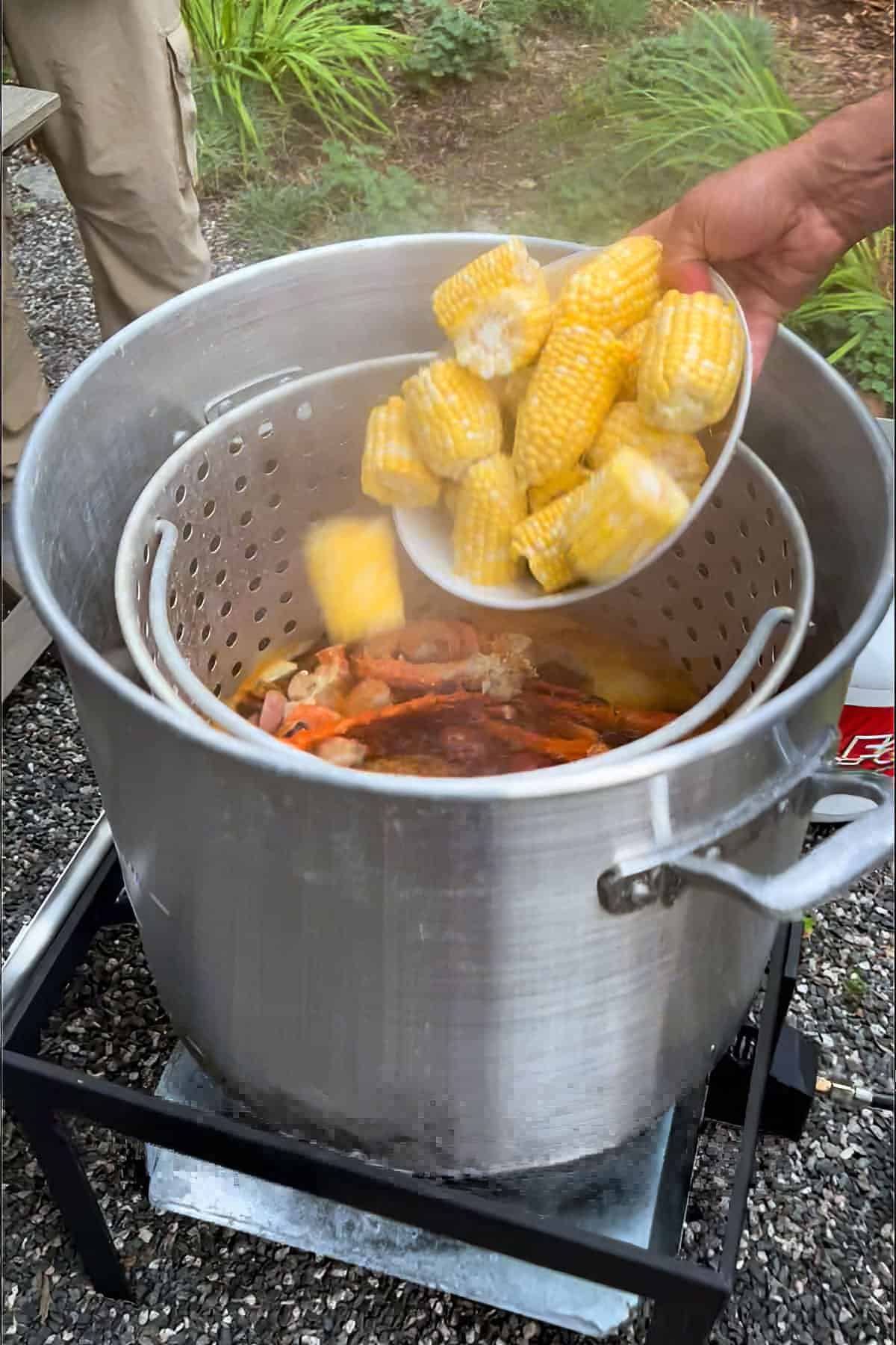 corn being added to a seafood boil pot.