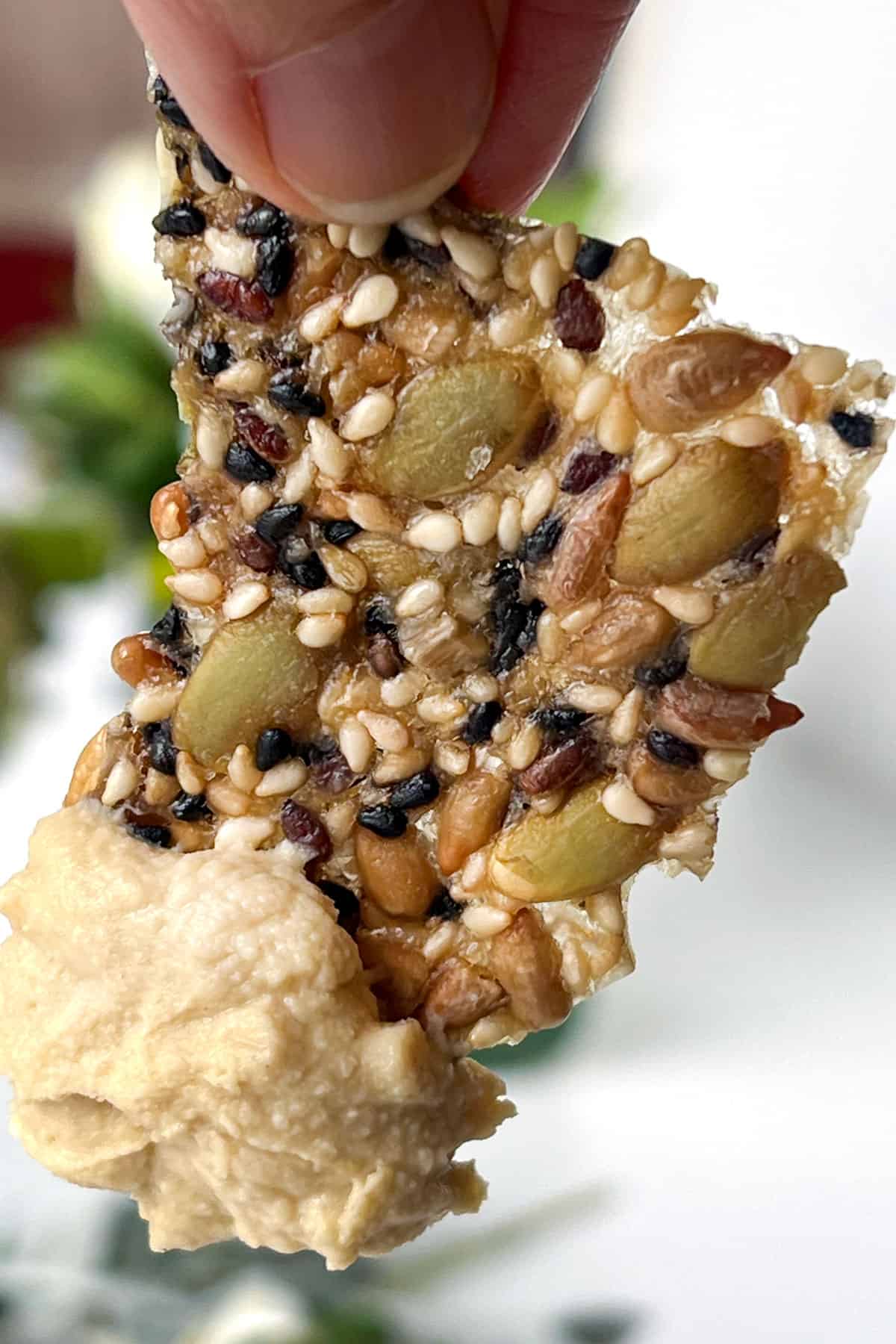 Thin seed cracker after being dipped into a tub of hummus.