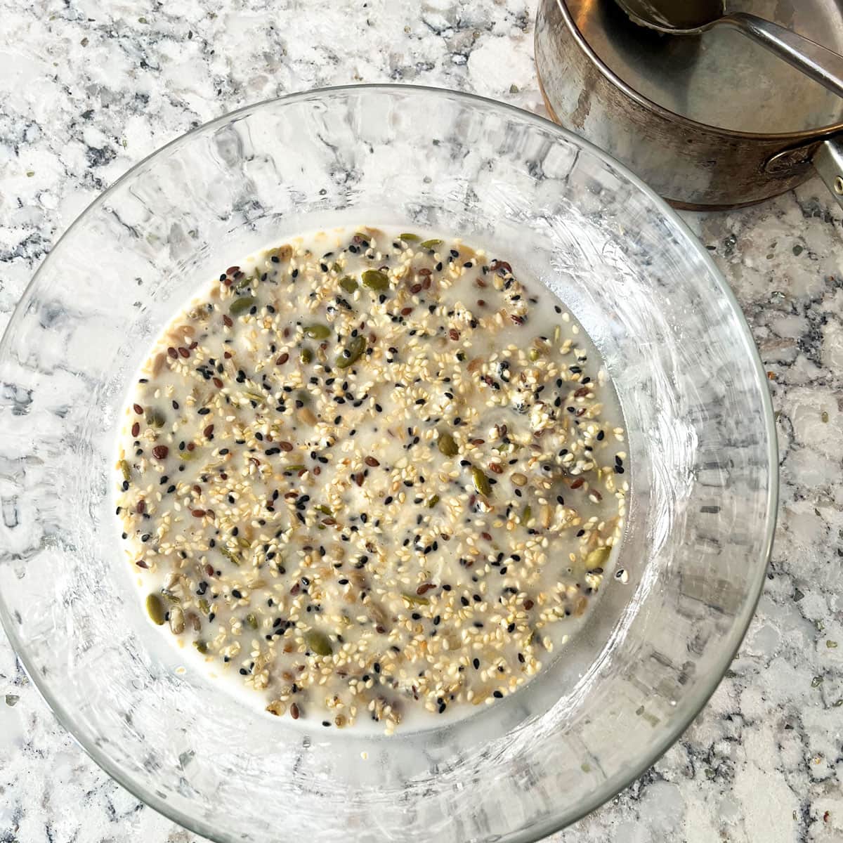 glass mixing bowl filled with a moist mixture of seeds and cornstarch.