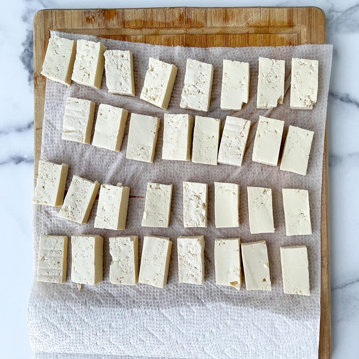 about 3 dozen small rectangular pieces of tofu set out on a paper towlel.