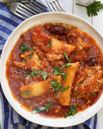 Greek chicken stew with potatoes and olives in a bowl with chopped parsley sprinkled on top