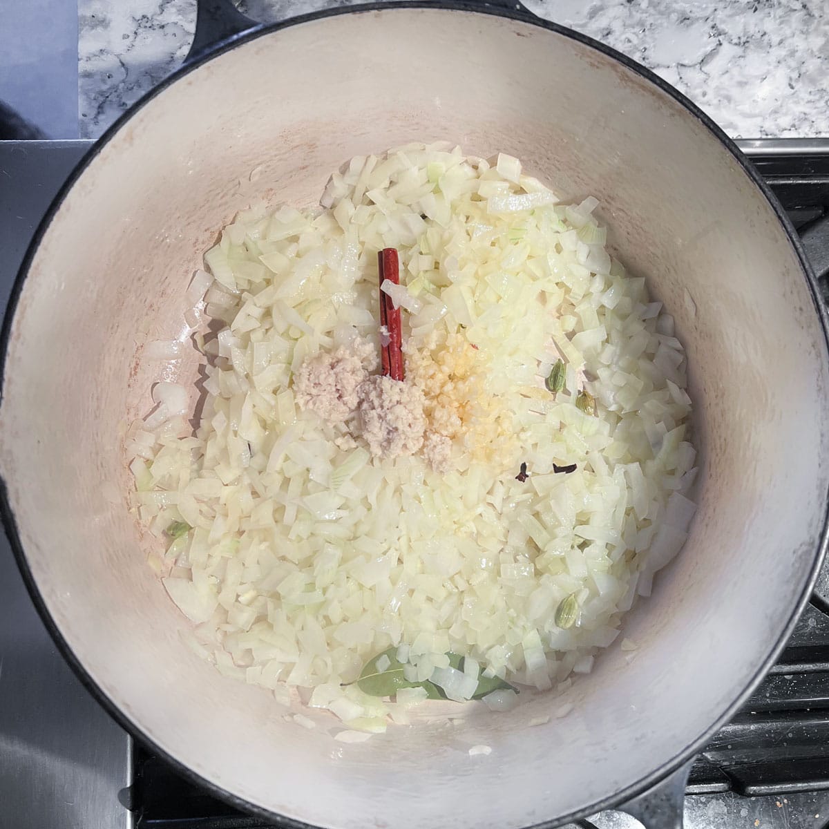 Dutch oven with chopped onions, minced garlic and grated ginger.
