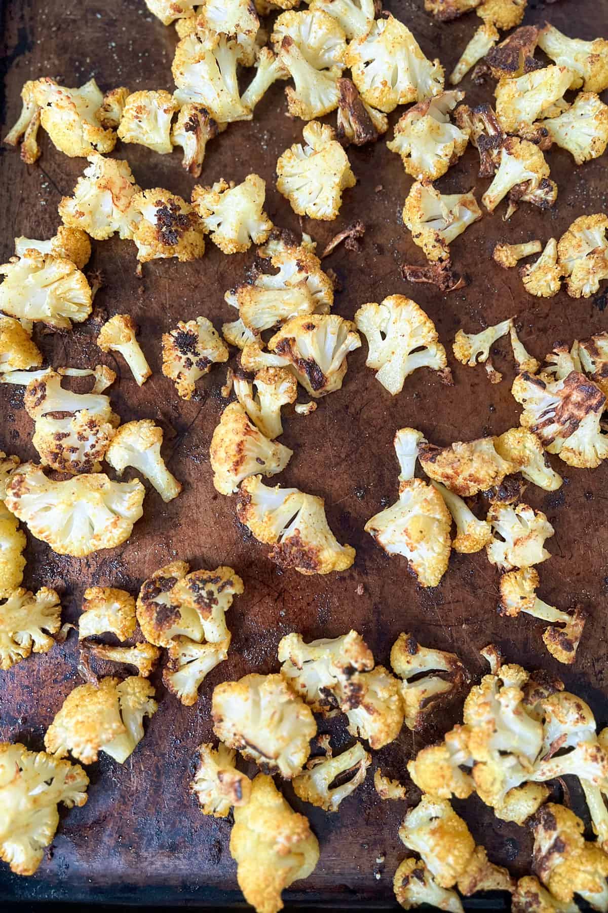 Roasted curried cauliflower on a rimmed baking sheet.