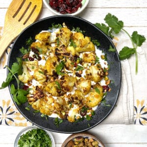 Curried roasted cauliflower on a bed of yogurt topped with chopped toasted pistachios and cilantro.