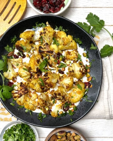 Curried roasted cauliflower on a bed of yogurt topped with chopped toasted pistachios and cilantro.