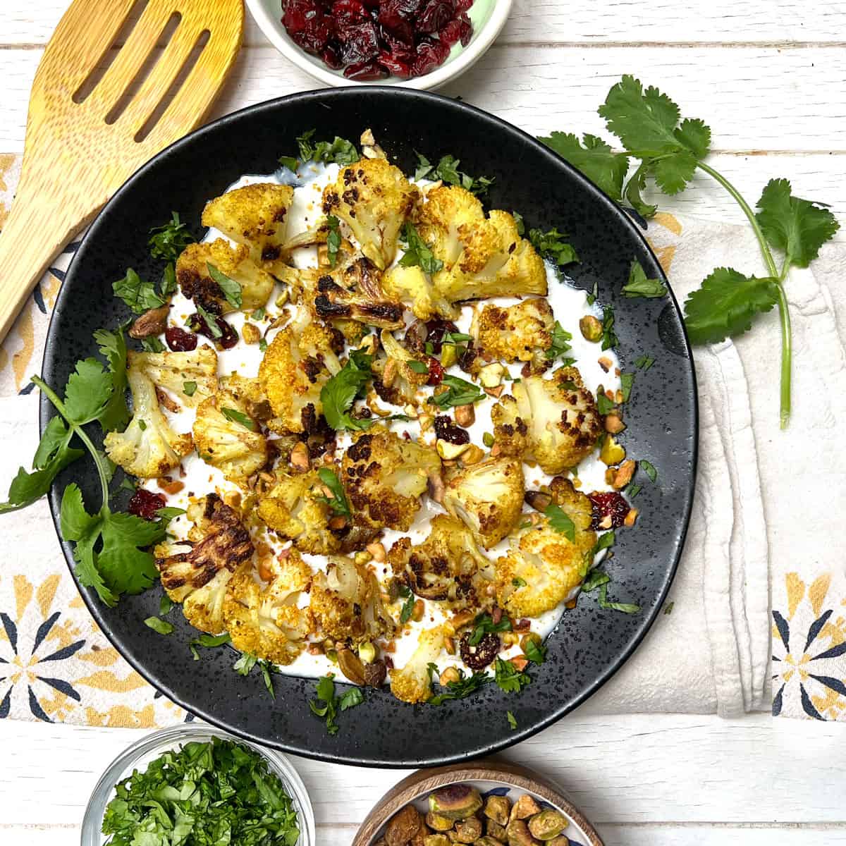 Curried roasted cauliflower on a bed of yogurt topped with chopped toasted pistachios and cilantro.