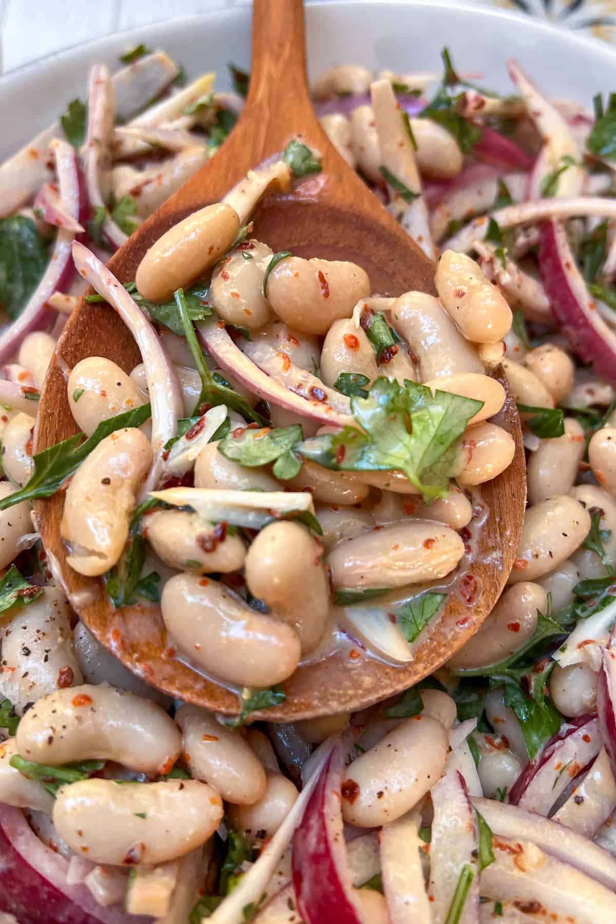 turkish white bean salad on a wooden spoon