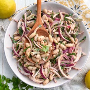 White bean salad with red onions and parsley in a bowl.