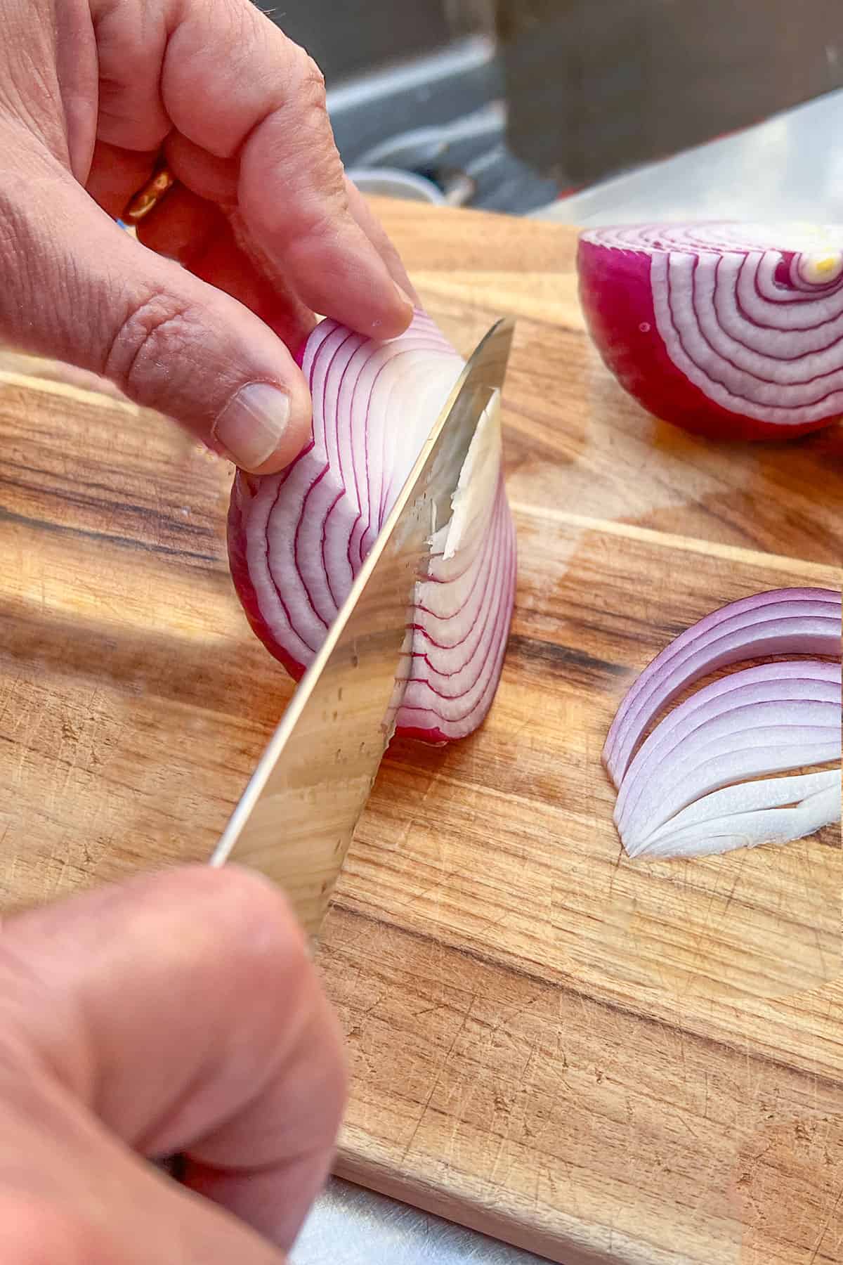 slicing a red onion into half moons for white bean salad.