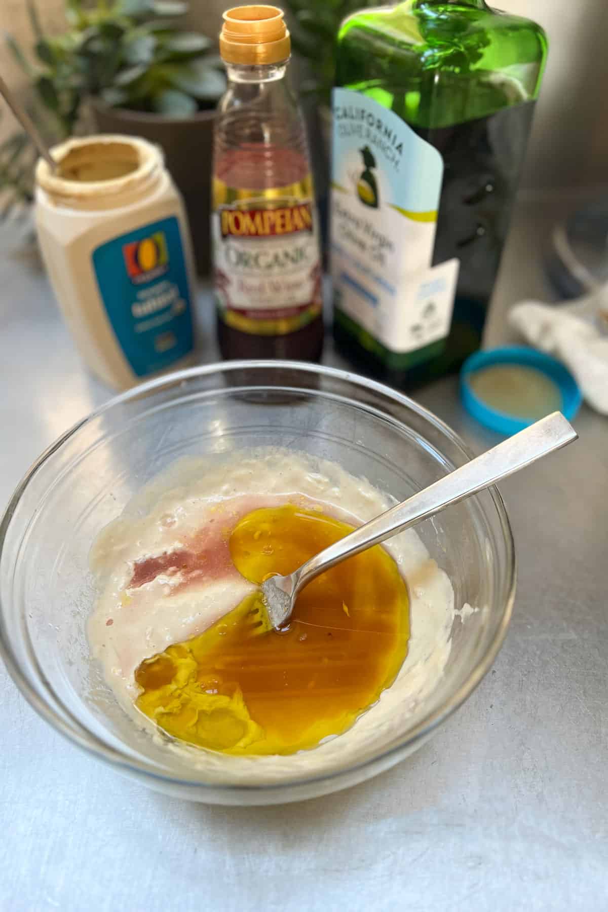 making tahini dressing for Turkish white bean salad in a glass bowl.