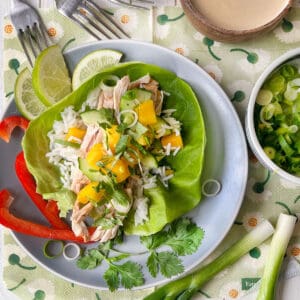 chicken mango lettuce wrap on a plate with lime wedges.