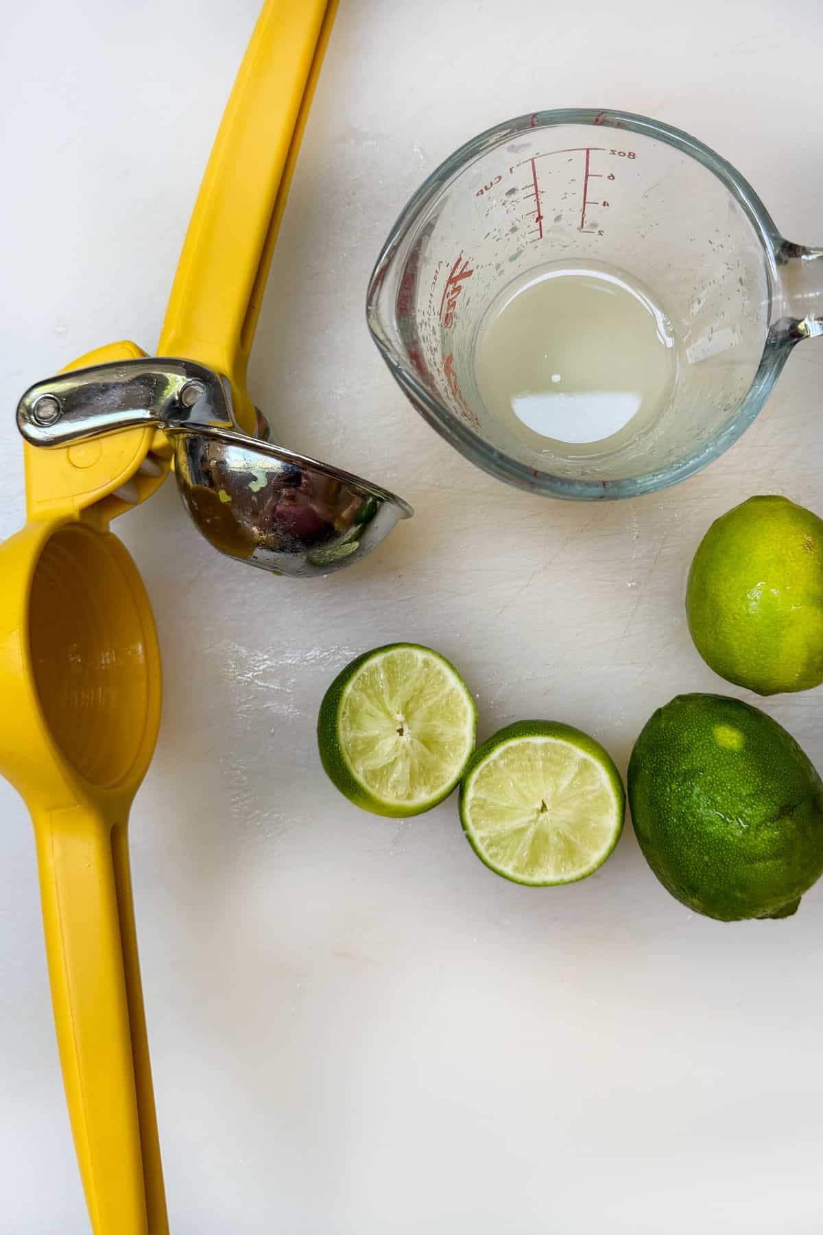 squeezing limes with a yellow citrus press, to make fresh lime juice.