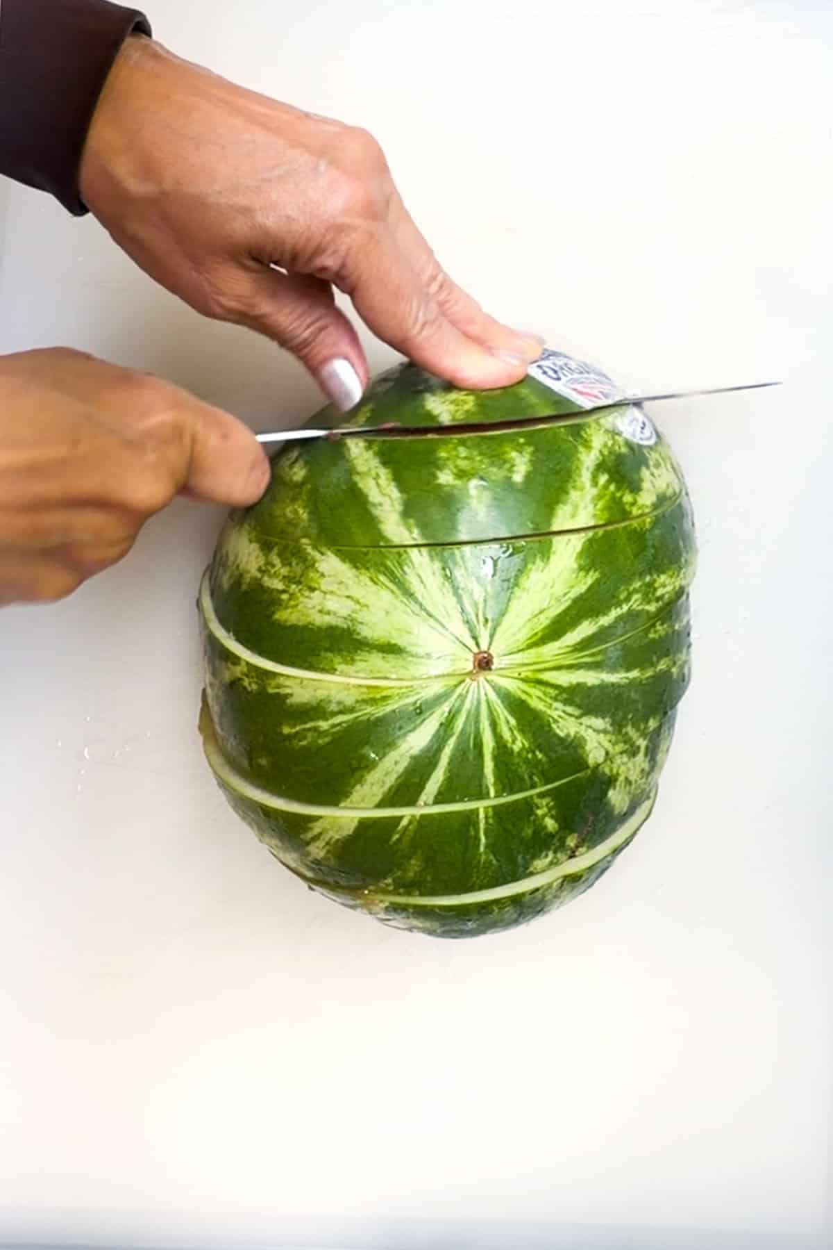 cutting half of a watermelon into 1-inch thick slices.