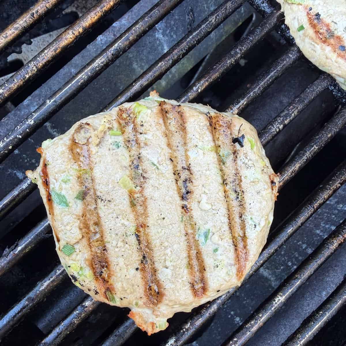 An ahi tuna burger on the grill with grill marks on the top.