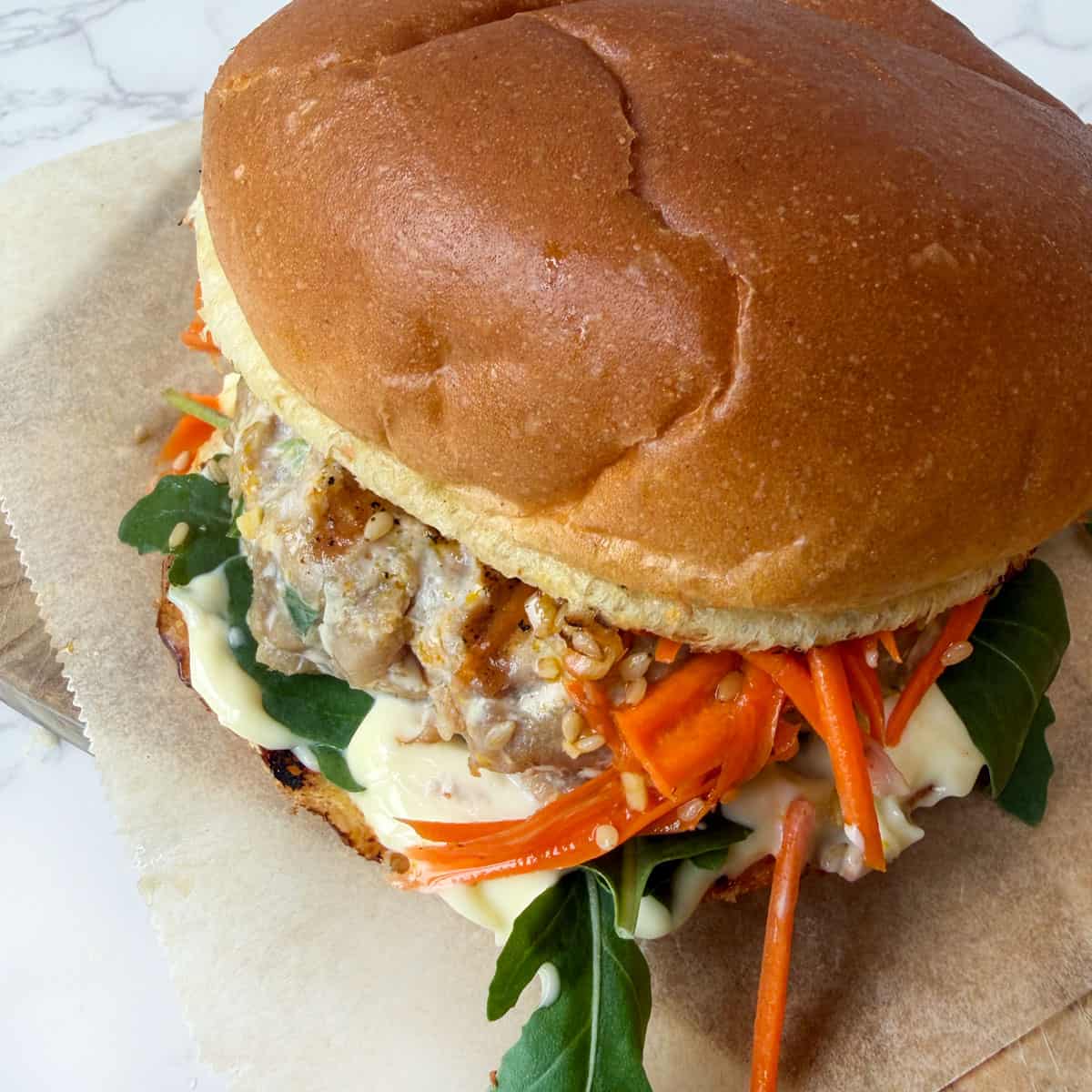 Ahi tuna burger on a brioche bun with kewpie mayo, arugula and carrot slaw.
