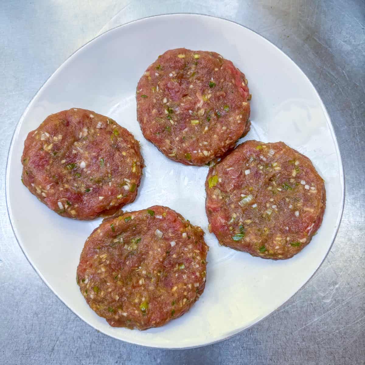 4 raw ahi tuna burger patties on a plate