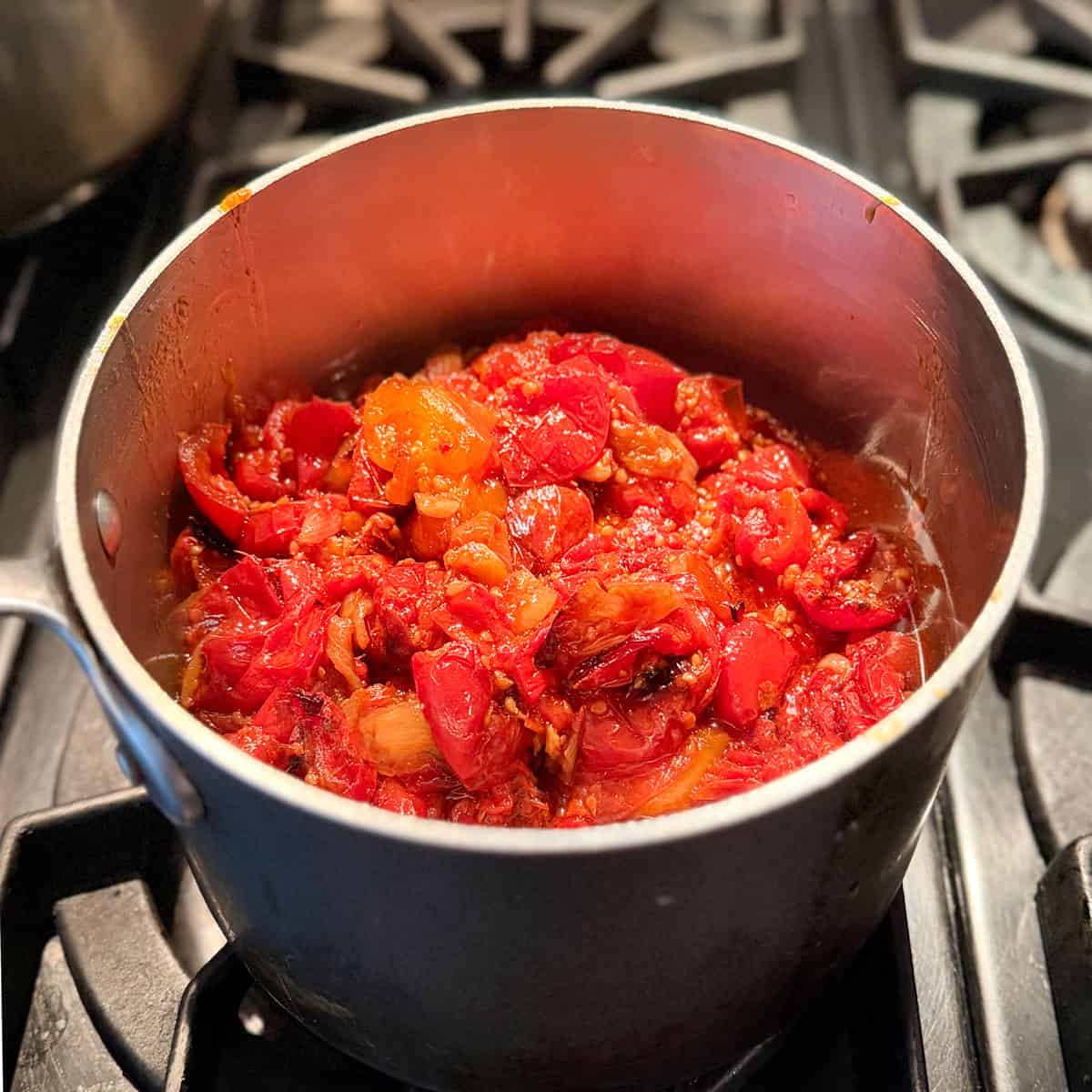 Chunky roasted fresh tomato sauce in a saucepan.
