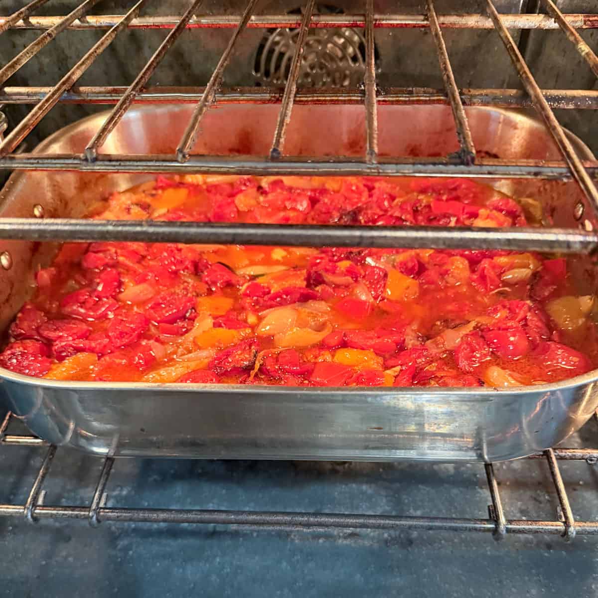 fresh cut-up tomatoes, onions and garlic roasting in the oven in a roasting pan.