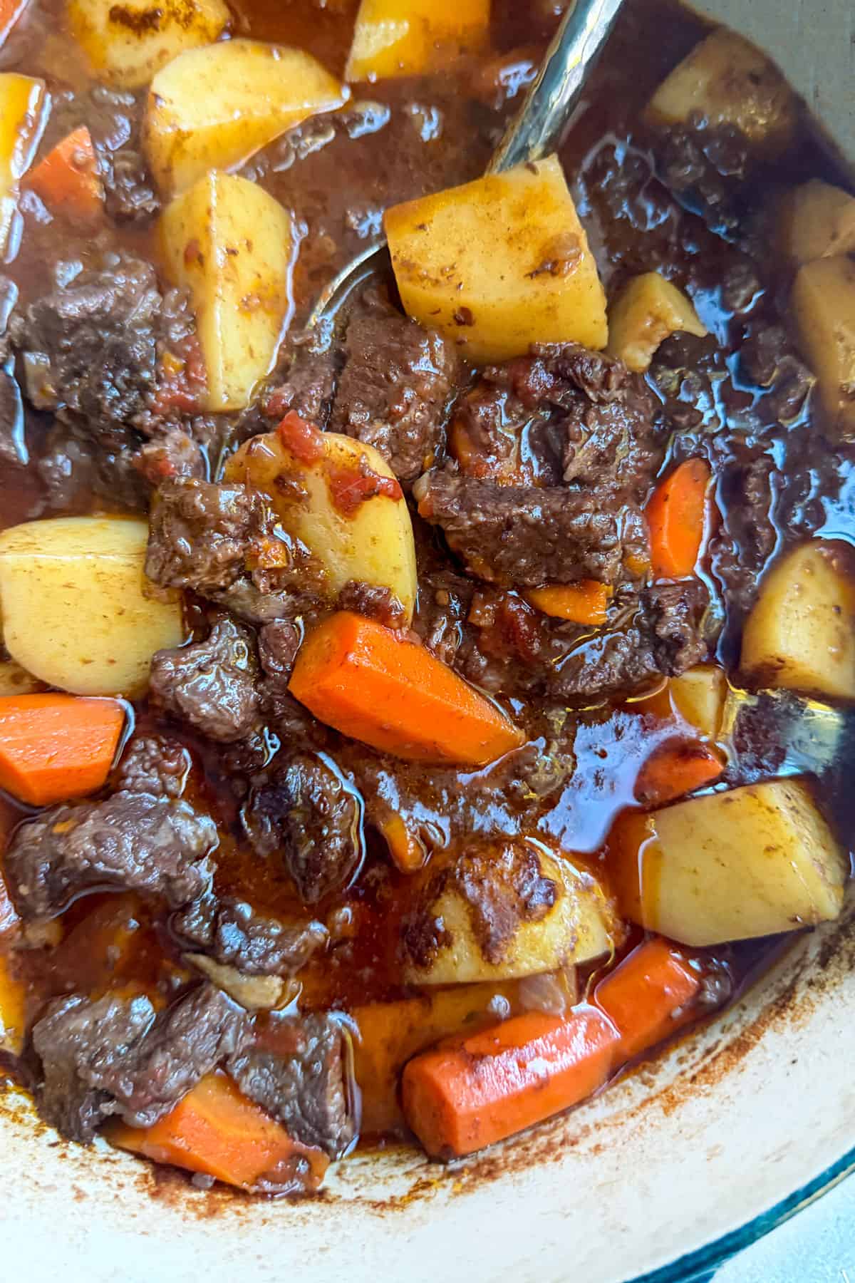 beef stew with chunks of carrots and potatoes, in a dutch oven.
