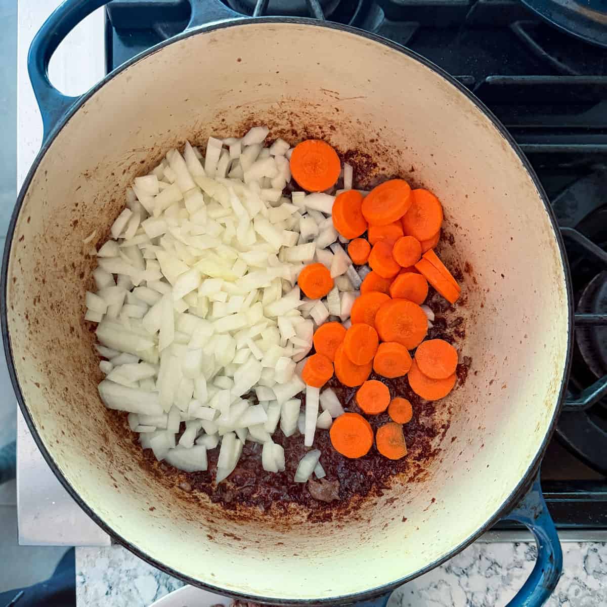 Raw chopped onions and sliced carrots in a dutch oven.